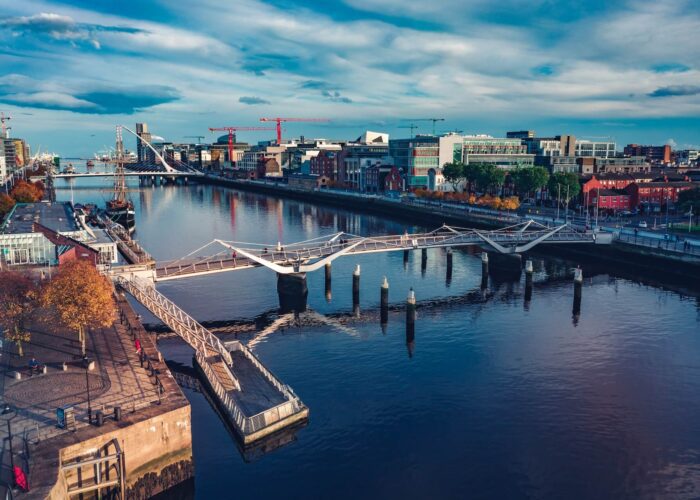 A silver bridge, wide blue river and the city skyline, in Dublin. Photo: Lucian Petronel