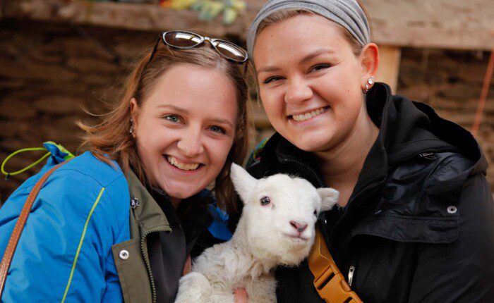 Friends holding baby lamb in Co. Kerry, Ireland