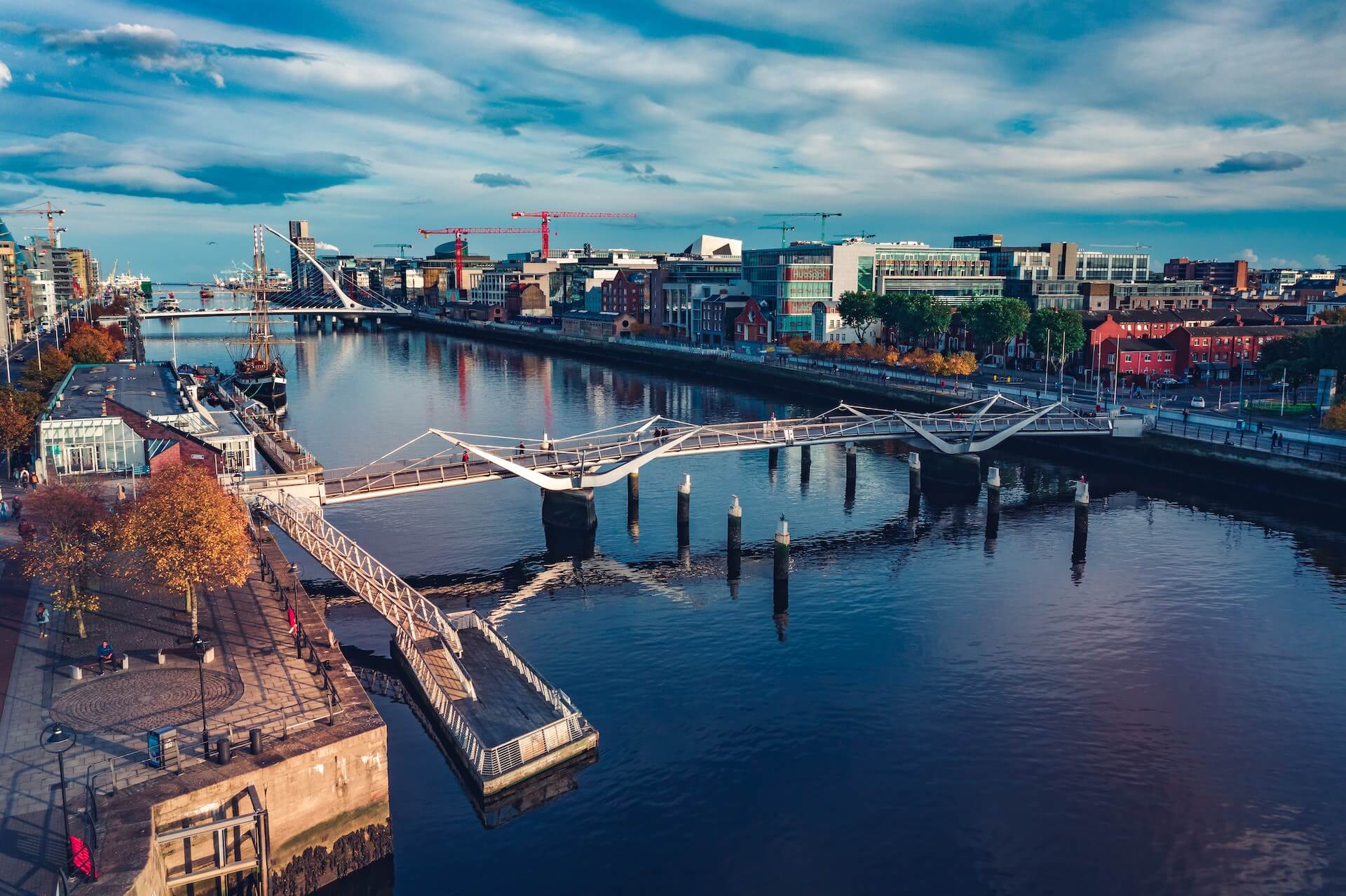 A silver bridge, wide blue river and the city skyline, in Dublin. Photo: Lucian Petronel